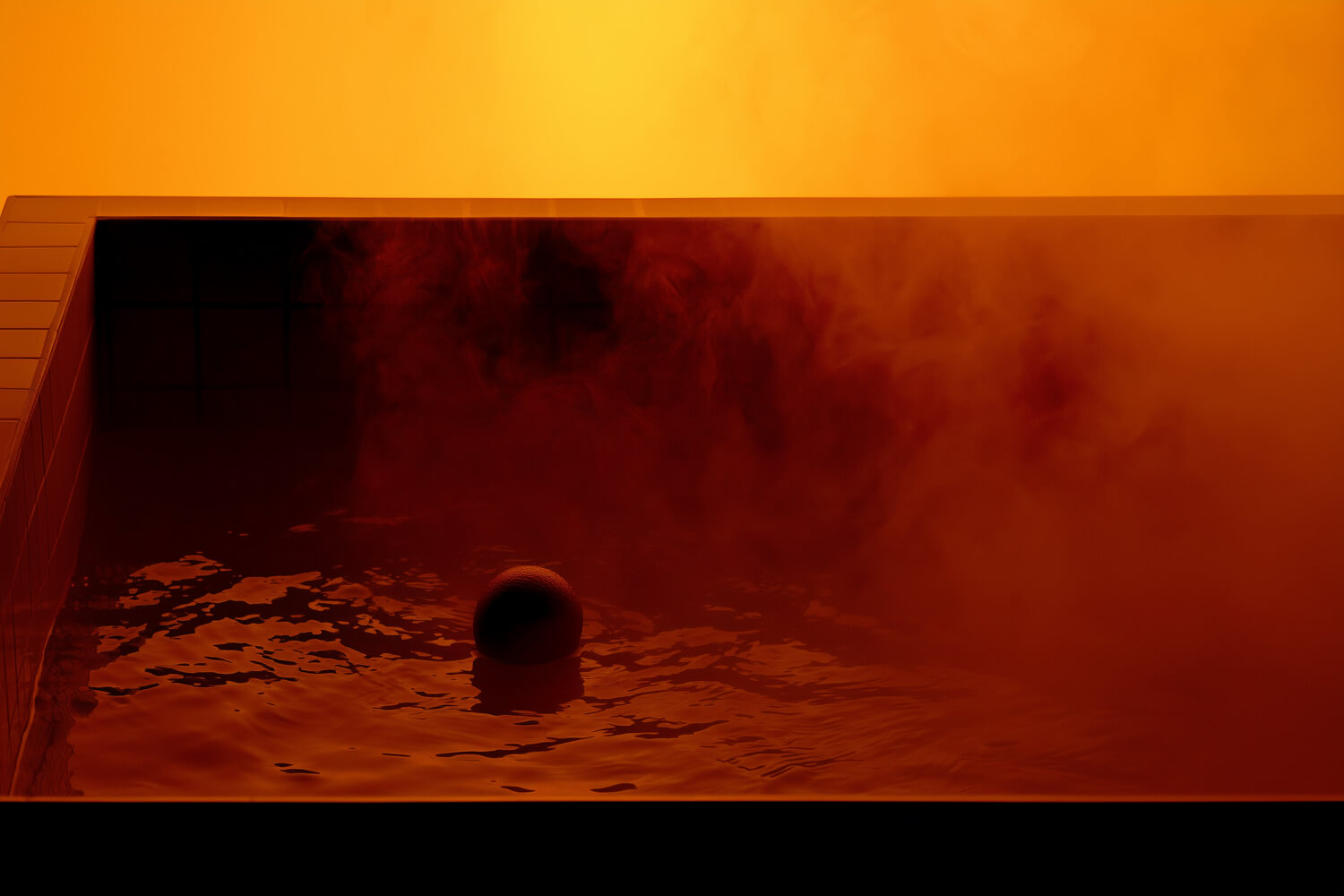 Lone swimmer in a steaming tiled pool, lit amber